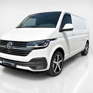 White VW passenger/cargo van shown in a 3/4 front view with black grille, large headlights, and silver alloy wheels in a studio setting
