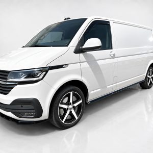 White cargo van angled view in a studio setting, showcasing front grille and side profile with black accents.
