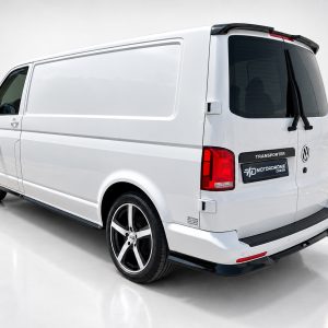White VW Transporter van viewed from the rear-right, showing large cargo area and tinted rear window with custom black wheels logo on the back door area