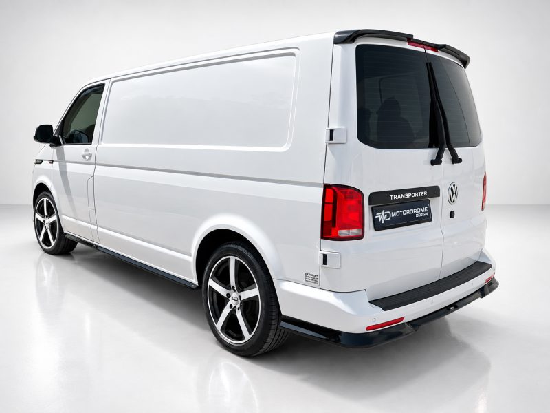 White VW Transporter van viewed from the rear-right, showing large cargo area and tinted rear window with custom black wheels logo on the back door area