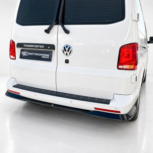 Rear view of a white Volkswagen Transporter van, showing the VW emblem, rear doors, and vertical wipers in a clean studio setting.