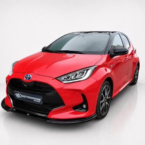 Red Toyota hatchback in a studio setting, angled front-left view showing glossy red paint and black accents on the roof and bumper.