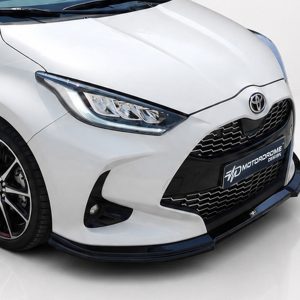 Front-left view of a white car showing the headlight, grille, and Toyota emblem on the hood.