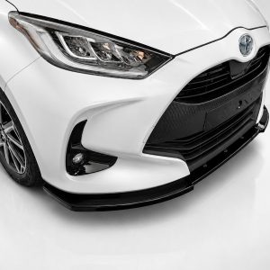 Front-left view of a white Toyota showing the headlight, grille, and front bumper with a carbon-fiber texture detail at the lower grille area.