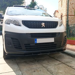 Front view of a white Peugeot van parked on a tiled street, with a black grille and emblem visible.