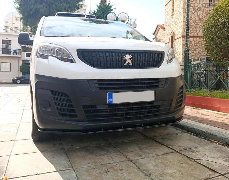Front view of a white Peugeot van parked on a tiled street, with a black grille and emblem visible.