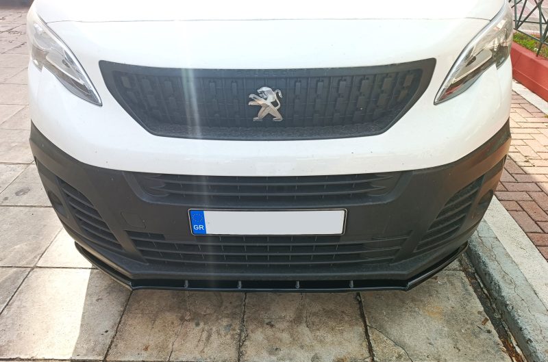 Close-up front view of a white Peugeot vehicle showing the black grille with a silver lion emblem and a European license plate partially visible.