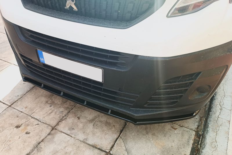 Front view of a white vehicle showing the grille with a Peugeot emblem and a blue GR license plate area at the lower left of the bumper.
