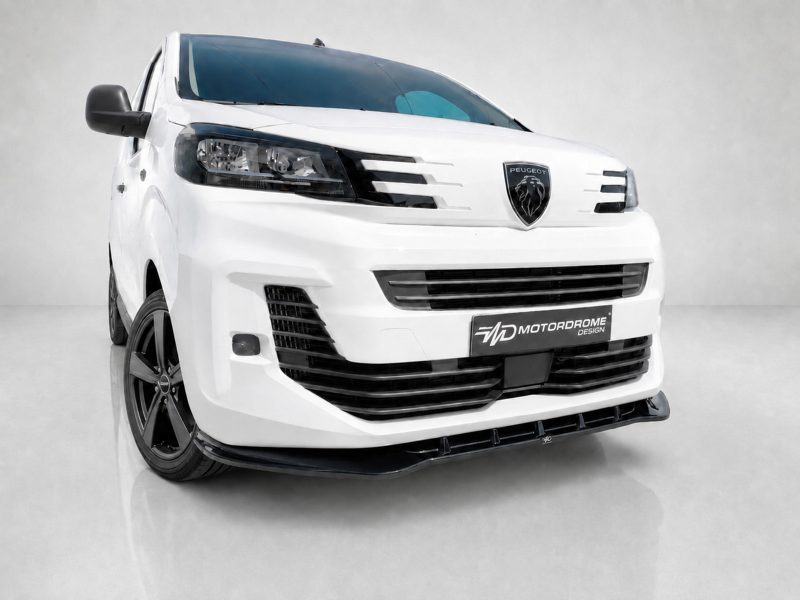 White Peugeot van shown from a front-left angle with bold grille and custom MD Motorodrome plate on the bumper