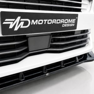 Close-up of a white truck front featuring a black Motordrome Design plate on the grille.