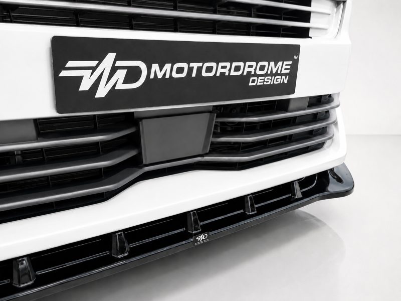 Close-up of a white truck front featuring a black Motordrome Design plate on the grille.