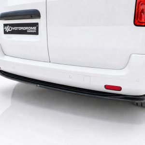 Rear view of a white van's back, showing a black Motordrome Design badge on the tailgate and the bumper area with red taillights to the sides.