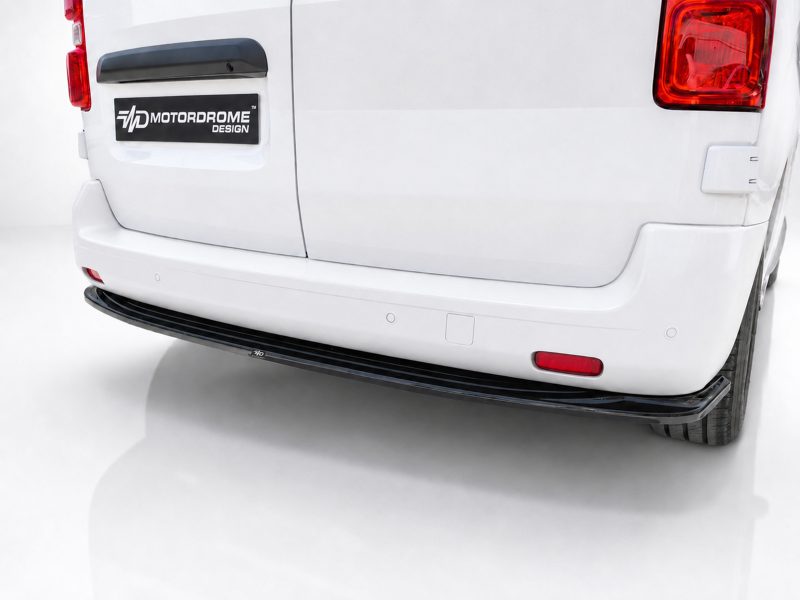 Rear view of a white van's back, showing a black Motordrome Design badge on the tailgate and the bumper area with red taillights to the sides.