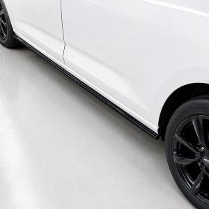 White car body with a black multi-spoke wheel shown from the side, focusing on the lower panel and tire on a light showroom floor.