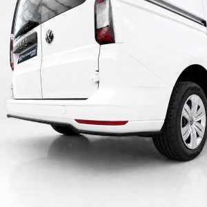 White VW van seen from the rear-right, showing taillight, bumper, and a visible wheel with the VW emblem.