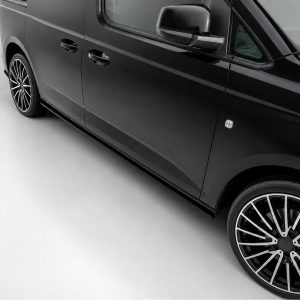 K172-005_2jpg - OPSHOLDERS Close-up of a glossy black van's side with chrome door handles and large multi-spoke alloy wheel on a light-gray floor