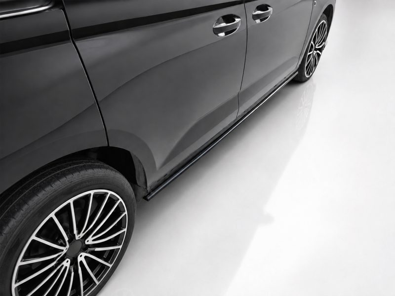 K172-005_3jpg - OPSHOLDERS Side view of a sleek black car showing its glossy door panels and large alloy wheel on a white floor surface