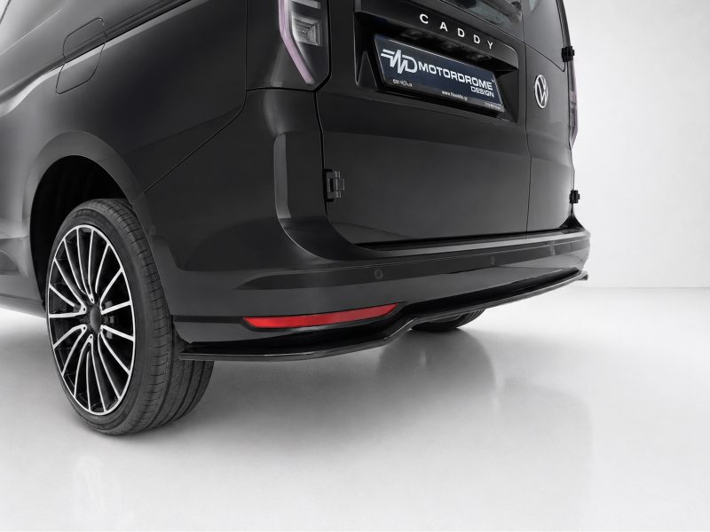Rear of a black van showing a stylish alloy wheel, taillight, and red rear reflector on the bumper.