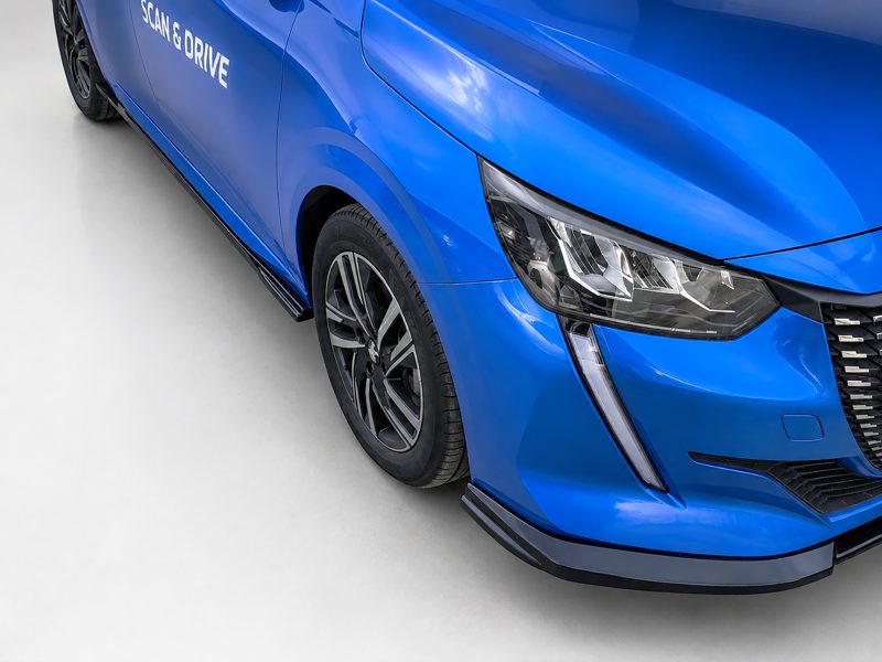 Close-up of a glossy blue car showing the front headlight, wheel, and 'Scan & Drive' text on the door section.