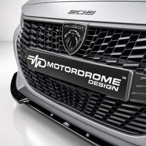 Close-up of the front grille on a Peugeot vehicle, featuring the lion emblem and a MotorDrome Design license plate.