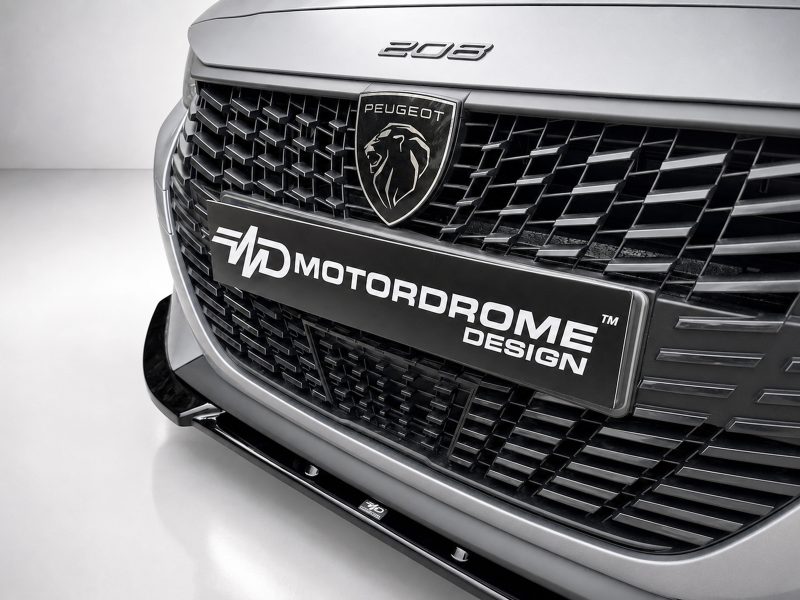 Close-up of the front grille on a Peugeot vehicle, featuring the lion emblem and a MotorDrome Design license plate.