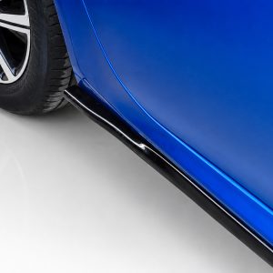 Close-up of a blue car's lower body panel, chrome trim, and a black side skirt beside the wheel.