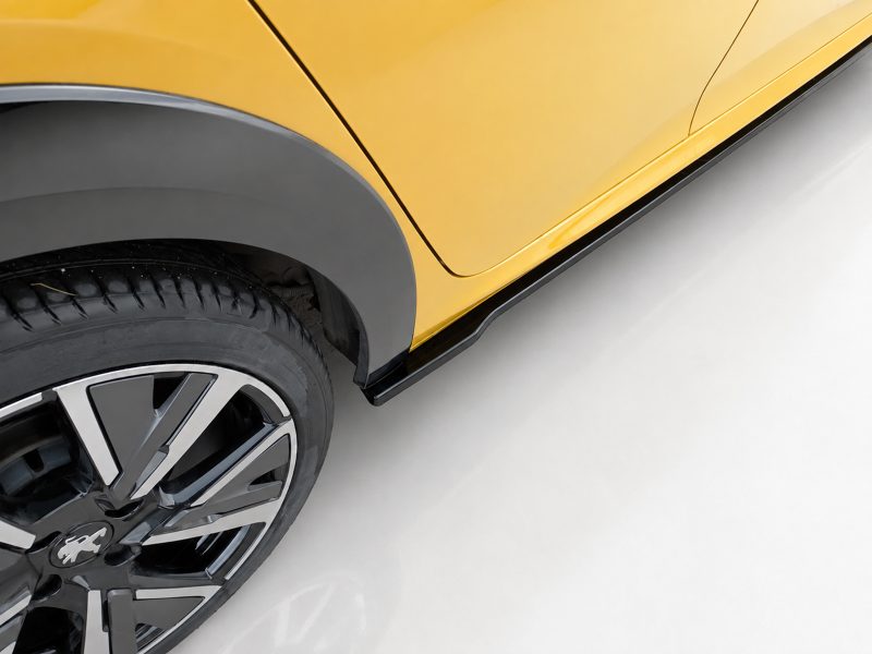 Close-up of a yellow car showing the front wheel with a black fender flare and a lower black side step along the body.
