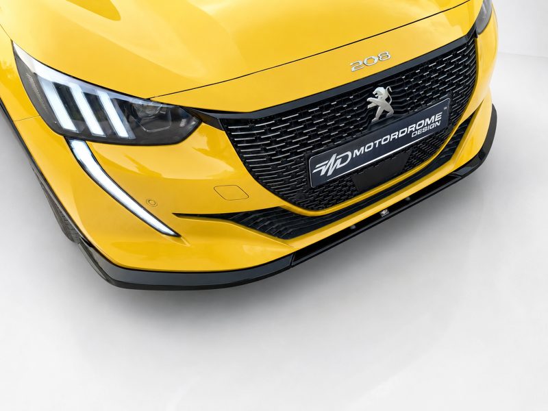 Front view of a bright yellow Peugeot 208, showing the grille, sharp headlight with LED strip, and a black plate reading 'Motordrome Design'