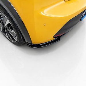 Rear corner of a yellow sports car showing the wheel, black fender arch, and lower aero lip/diffuser piece with glossy finish.