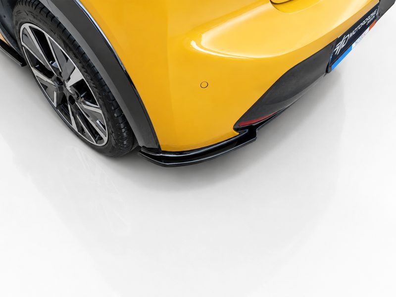 Rear corner of a yellow sports car showing the wheel, black fender arch, and lower aero lip/diffuser piece with glossy finish.