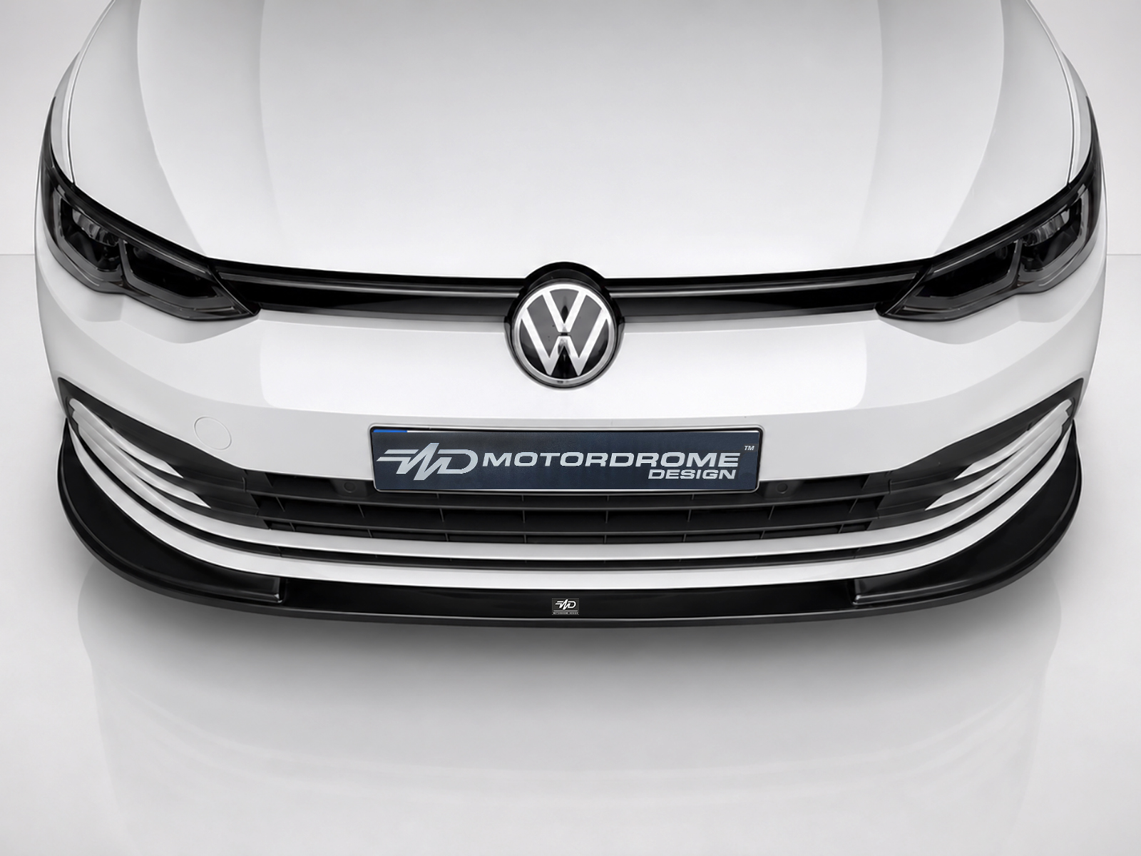 K174-001_2jpg - OPSHOLDERS Front view of a white Volkswagen with a black grille and a Motordrome Design plate in the center of the bumper.
