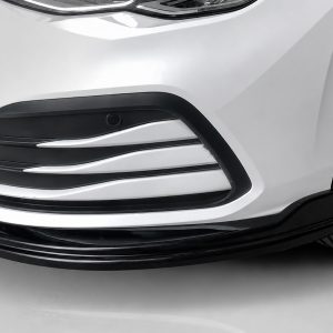 K174-001_3jpg - OPSHOLDERS Close-up of a white car's front bumper with black grille accents and a visible tire on the right edge.