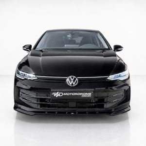Front view of a glossy black Volkswagen car in a bright studio, logo and Motordrome Design plate visible on the grille area