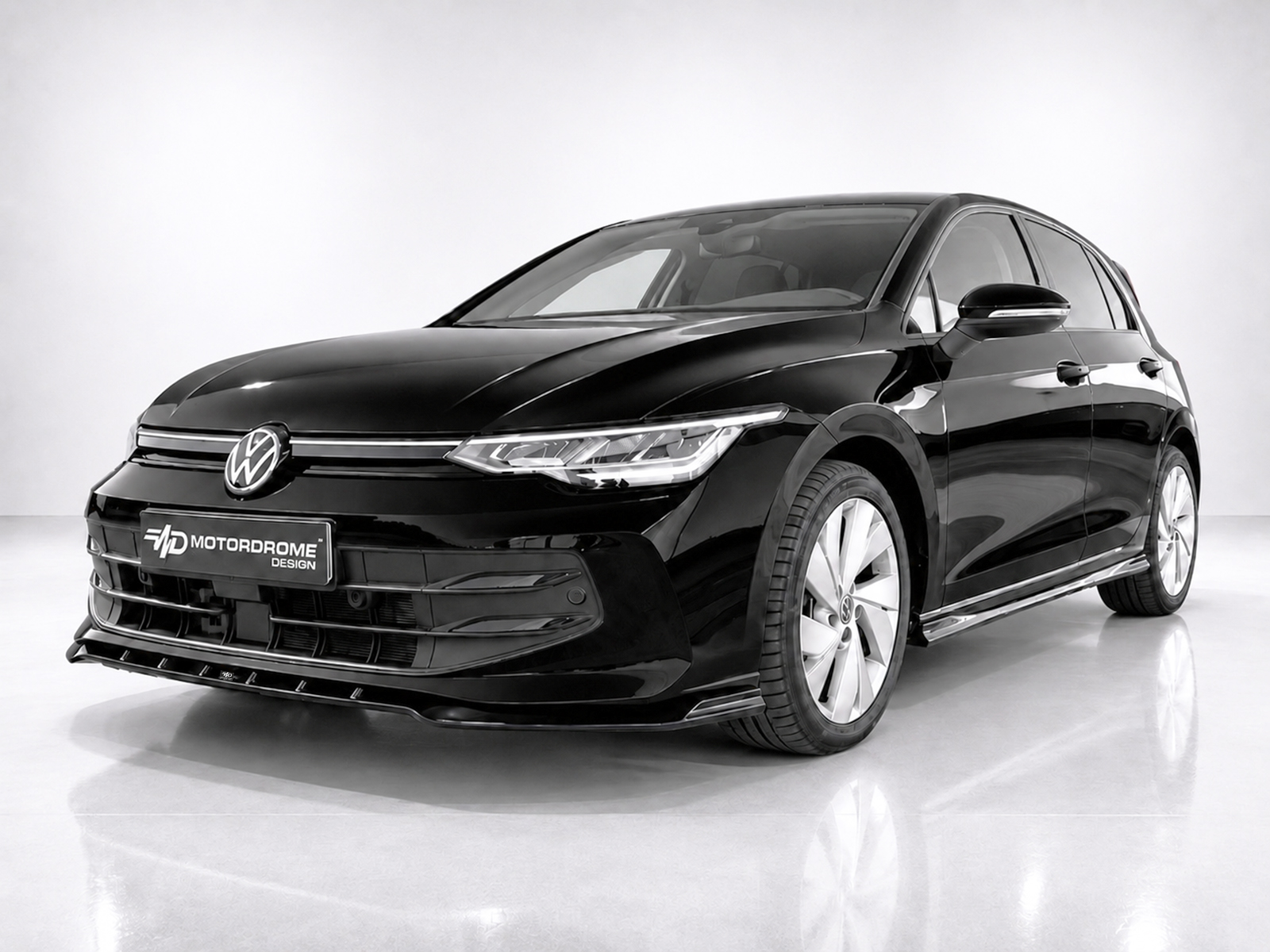 K174-002_2jpg - OPSHOLDERS Front three-quarter view of a sleek black Volkswagen sedan in a studio setting, chrome grille and VW emblem visible on the grille.