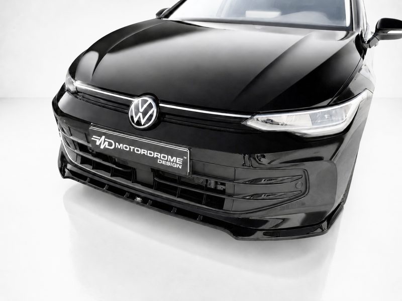 K174-002_3jpg - OPSHOLDERS Front view of a glossy black Volkswagen in a studio, displaying the logo and a Motordrome Design license plate on the bumper.