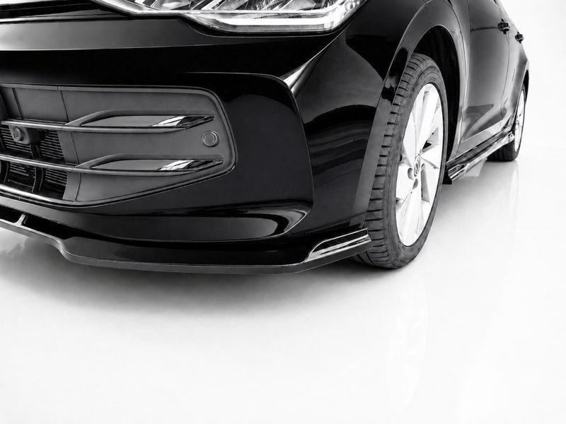 K174-002_4jpg - OPSHOLDERS Close-up of a glossy black car front with bumper and headlight, and the left front wheel visible on a white background.
