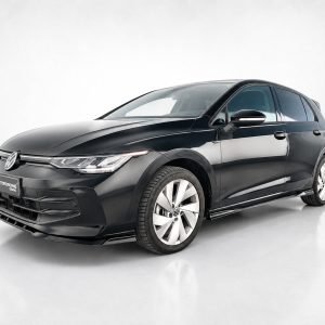 Front three-quarter view of a glossy black Volkswagen sedan in a bright studio setting, showcasing sleek lines and alloy wheels.