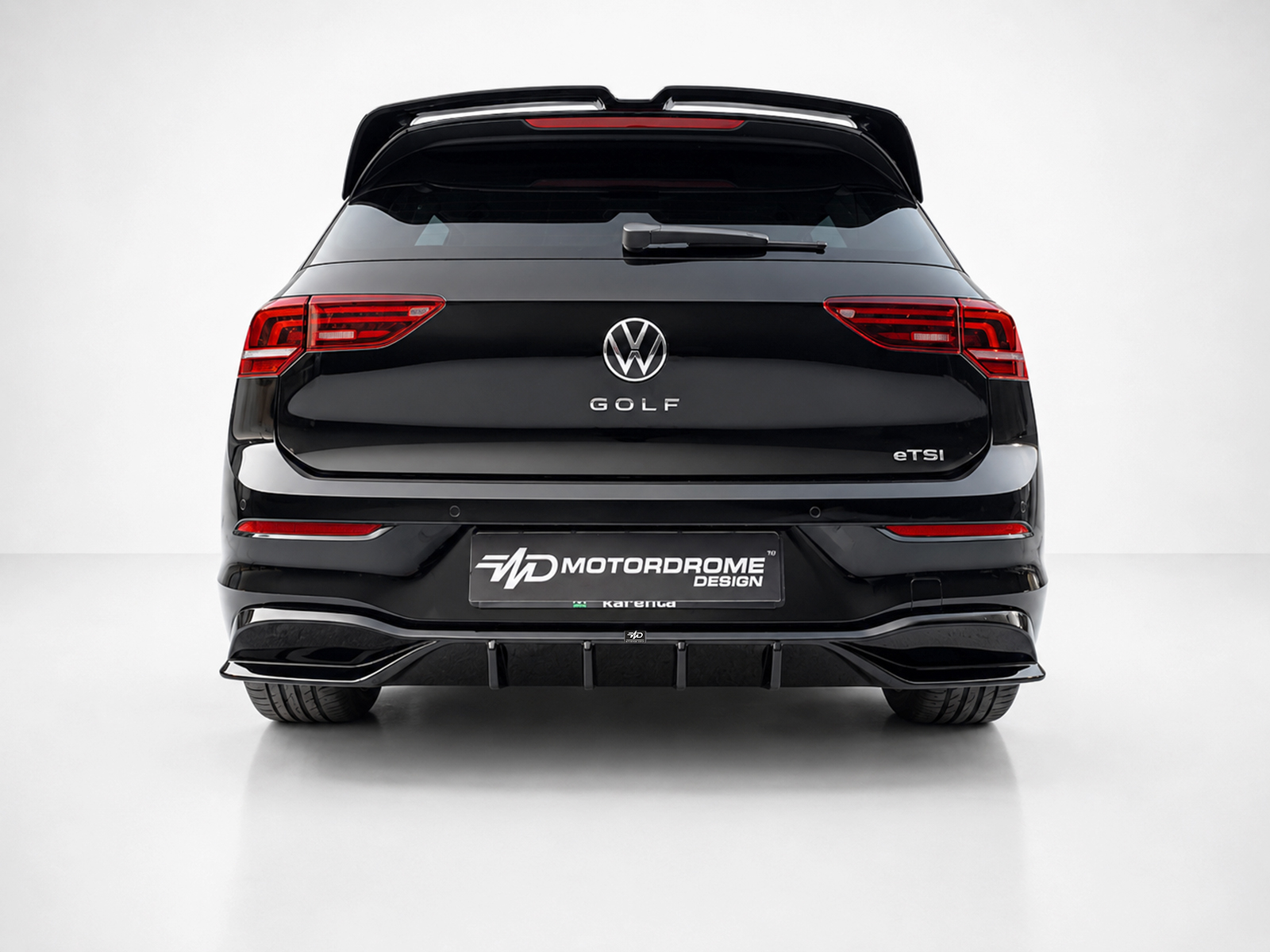 K174-004_1jpg - OPSHOLDERS Rear view of a black Volkswagen Golf eTSI with red taillights and a Motordrome Design plate on a white background; showroom photo.