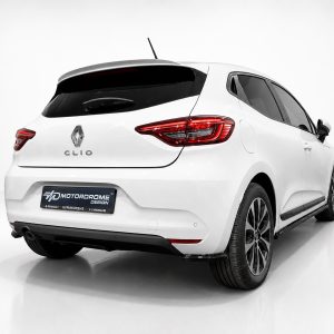 Rear three-quarter view of a white Renault Clio hatchback in a studio, showing the taillights and rear badge.