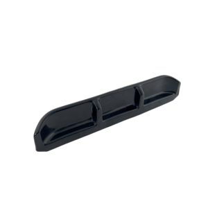 Long black plastic component with three rectangular depressions along its length and rounded ends, viewed at an angle.