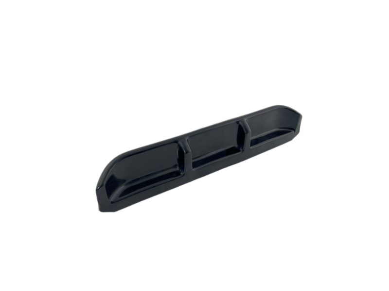 Long black plastic component with three rectangular depressions along its length and rounded ends, viewed at an angle.