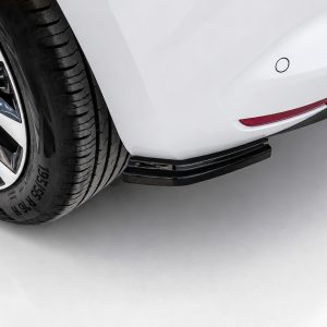 K175-004_3jpg - OPSHOLDERS Close-up of a white car's rear wheel and side step, showing a black tire, chrome rim, and red reflector on the bumper.