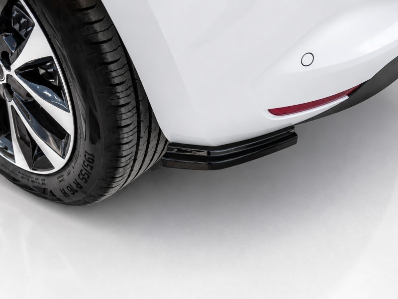 K175-004_3jpg - OPSHOLDERS Close-up of a white car's rear wheel and side step, showing a black tire, chrome rim, and red reflector on the bumper.
