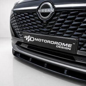 Close-up of a Nissan emblem on a glossy black grille with a diamond-patterned design and a Motordrome Design license plate.