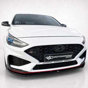 Front view of a white Hyundai car in a studio, showcasing a black honeycomb grille and sleek headlights.