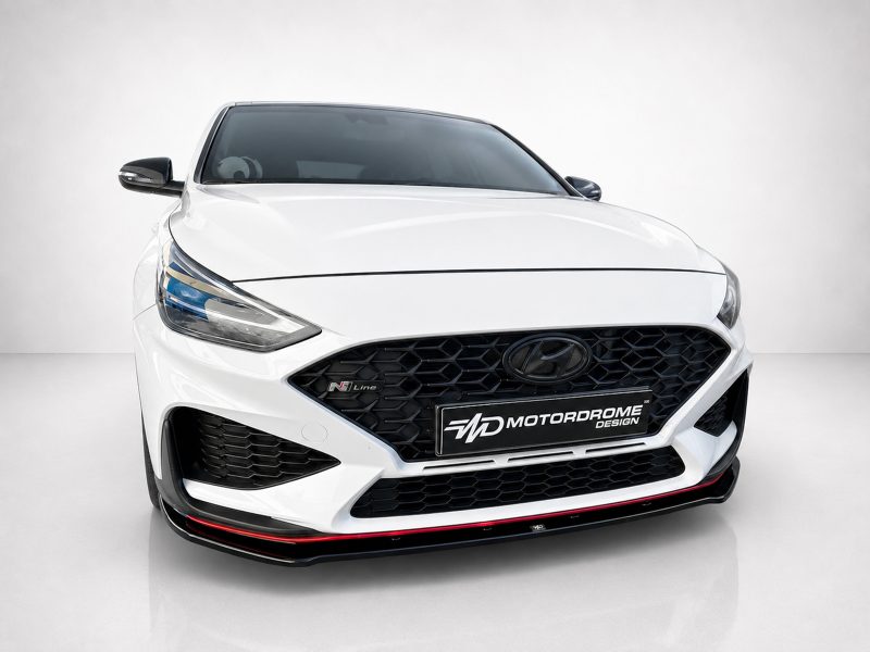 Front view of a white Hyundai car in a studio, showcasing a black honeycomb grille and sleek headlights.