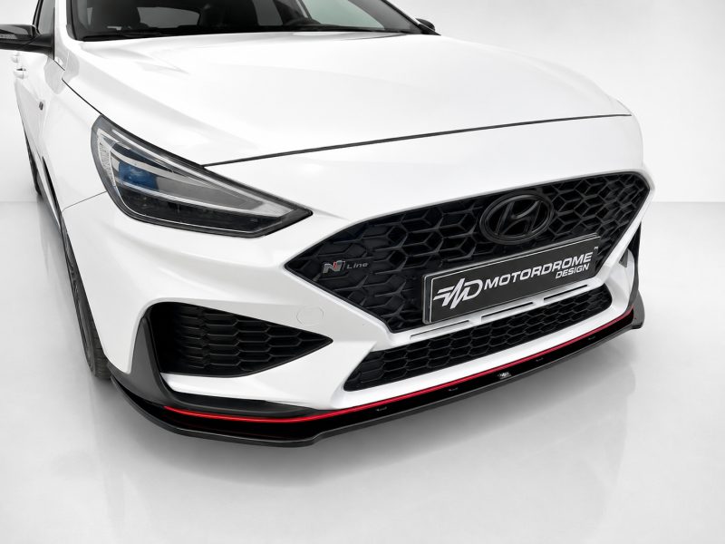 Front view of a white Hyundai with a black honeycomb grille, headlight on the left, and a red-accent lip under the bumper.