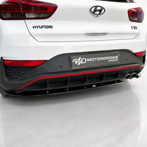K180-002_4jpg - OPSHOLDERS Rear view of a white Hyundai hatchback showing taillights, Hyundai badge, and a MotorDrome Design plate on the bumper with a black diffuser and red trim.