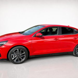 Side view of a shiny red four-door sedan with black alloy wheels in a studio setting.