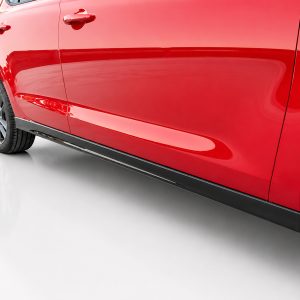 Red car side view showing front and rear door, wheel, and black side skirt on a white showroom floor